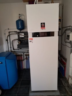De warmtepompboiler binnen. Op de achtergrond leidingen. Rechts nog een watervat van de oude installatie